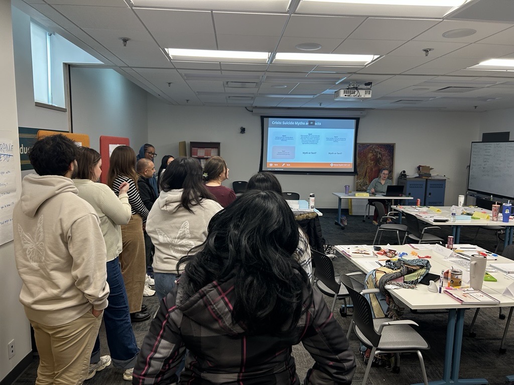 People standing and looking toward projector on the wall.